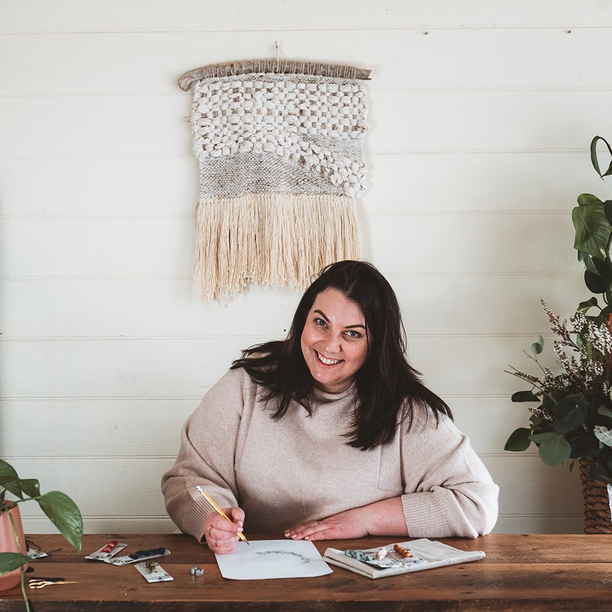 Amy Kallissa embroidery and patchwork designer sits at a desk to draw up a new design.