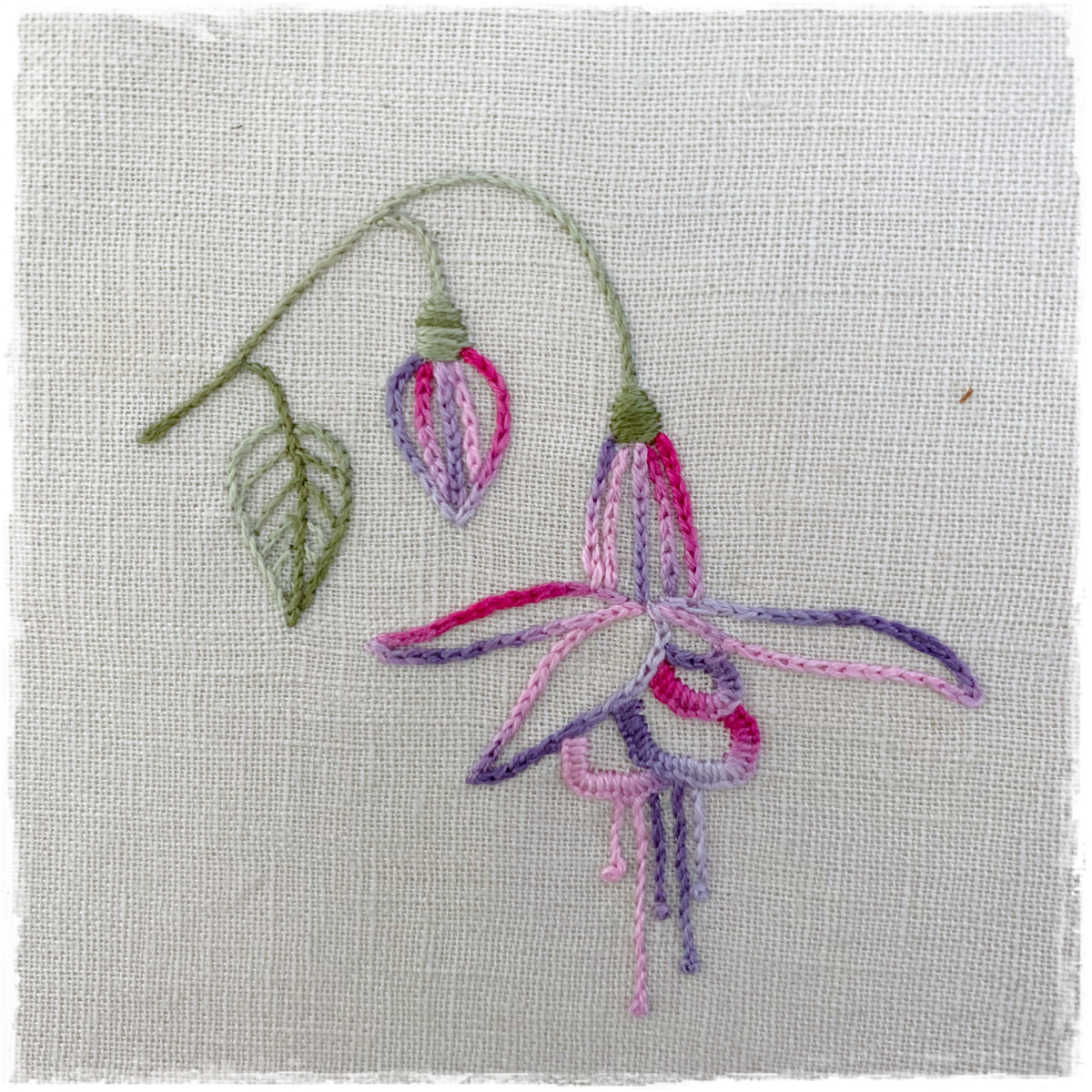 needlecraft pattern for a floral design, featuring instructions and a sample stitched on linen