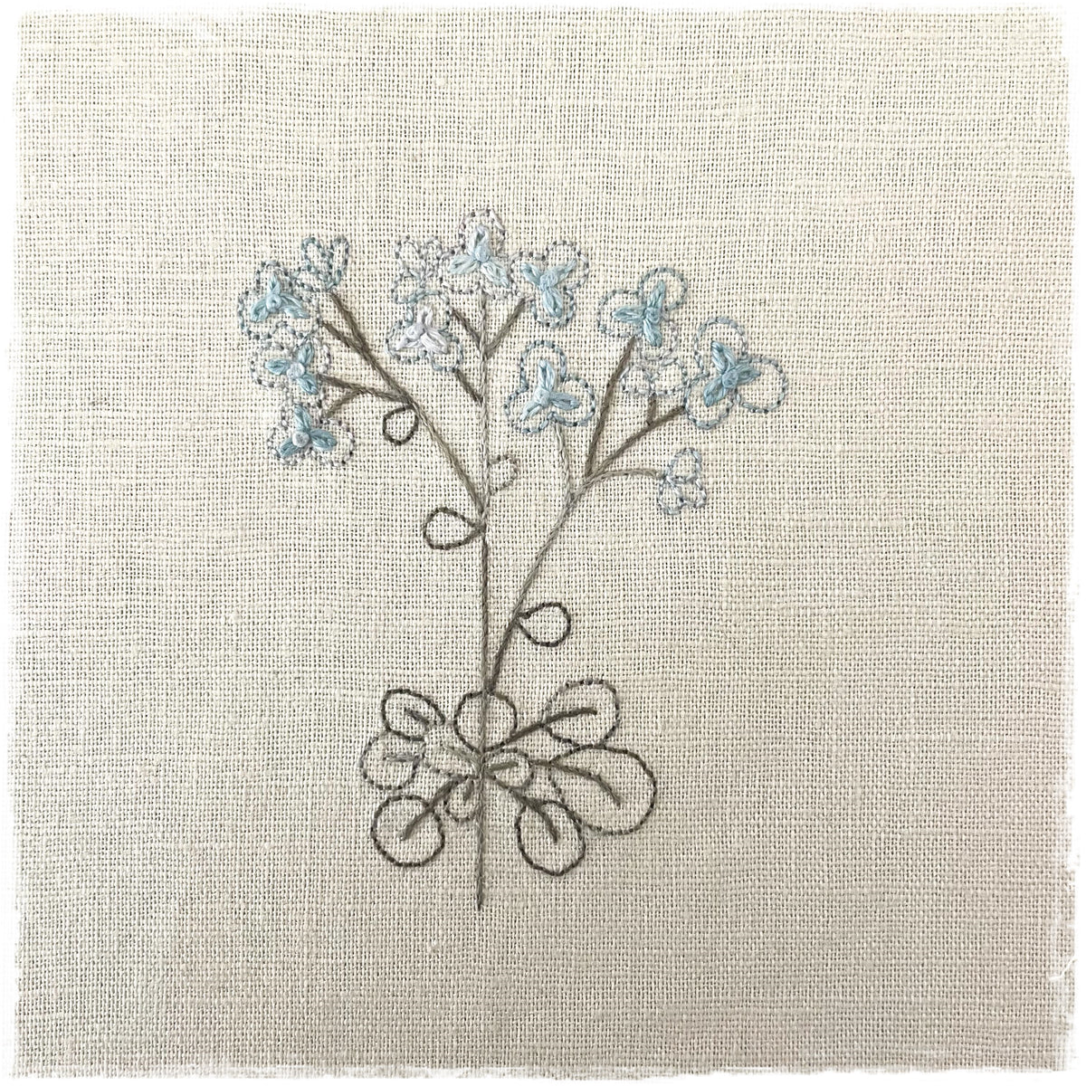quilting canvas with a floral design and blue flowers stitched on it.
