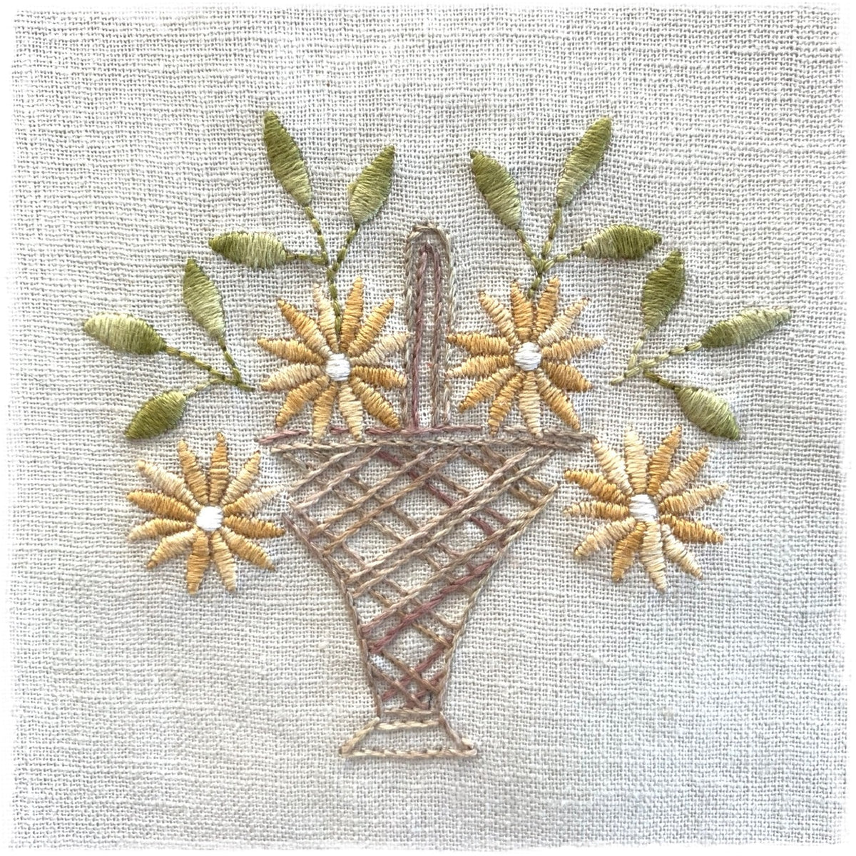 needlecraft pattern for a quilted basket with floral designs and tassels, stitched on a linen background