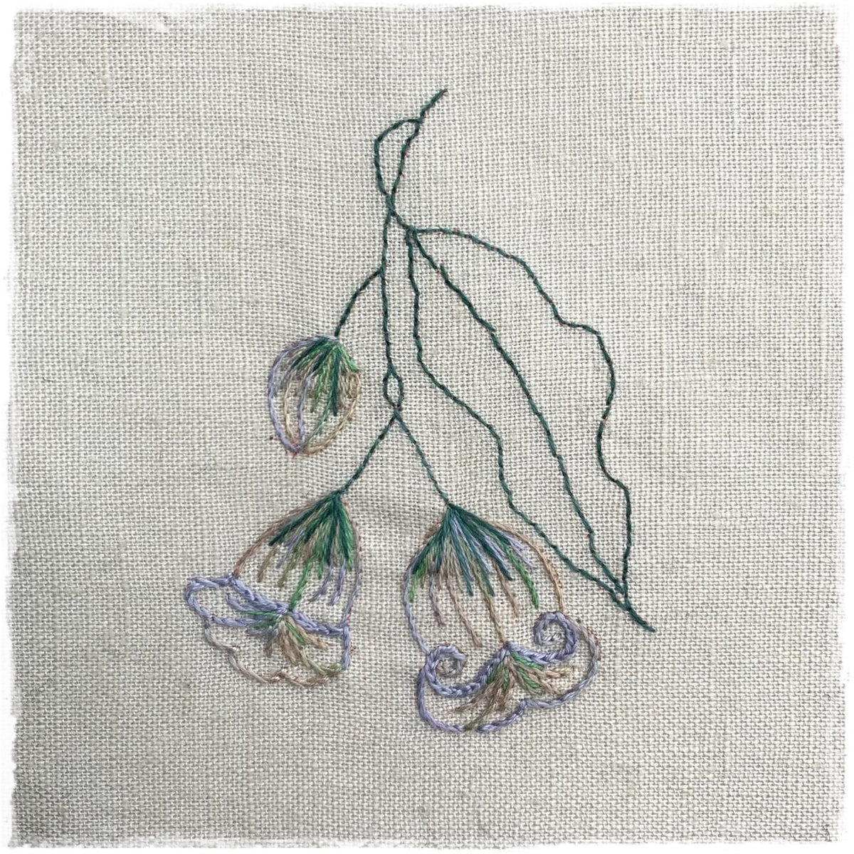 needlecraft pattern for a floral-themed quilt, showing a linen fabric with the stitched design of flowers and leaves