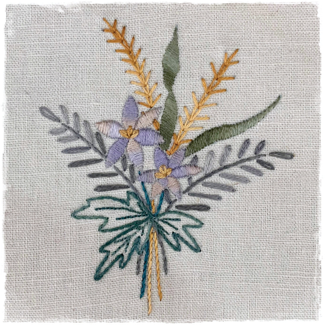needlecraft pattern featuring a floral design with various fabric colors stitched on a linen background