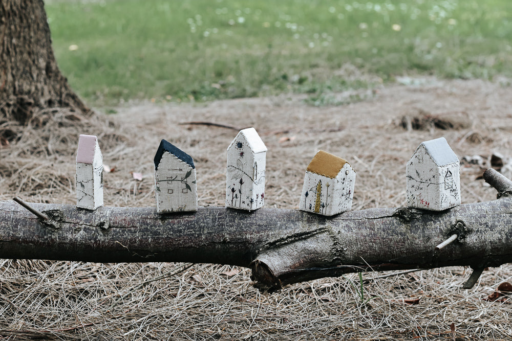 Photo of completed Hares Nest Stitchery Village sitting on a log