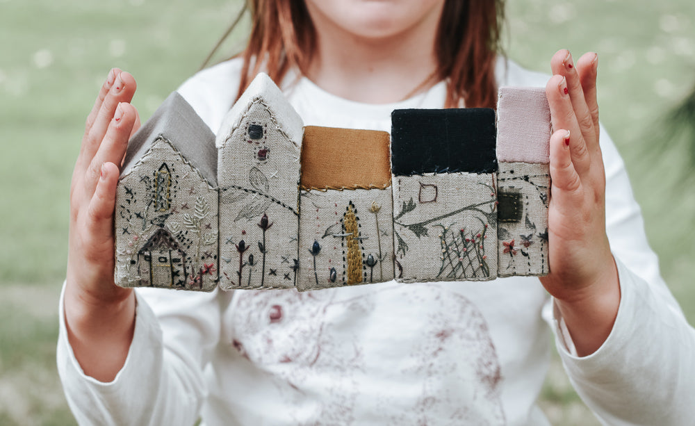 Picture of child holding embroidery houses in a row