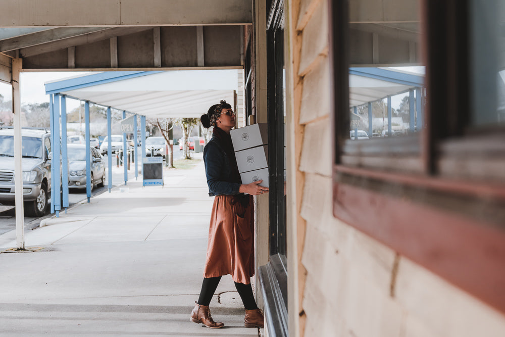 Katie walking into Cottage Garden Threads Studio holding three boxes