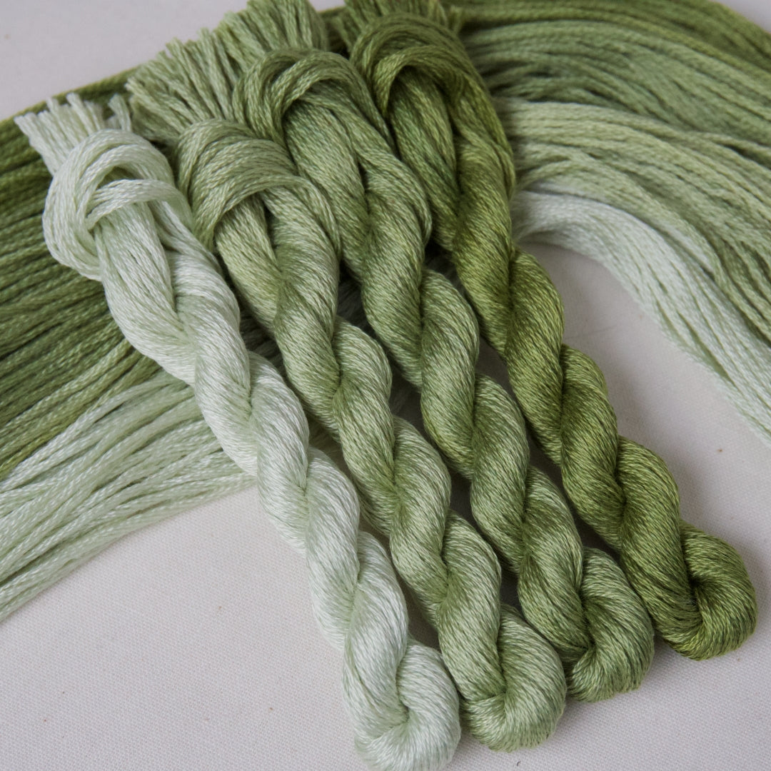 Four twisted embroidery threads in a gradient pack of clover green from light to dark.