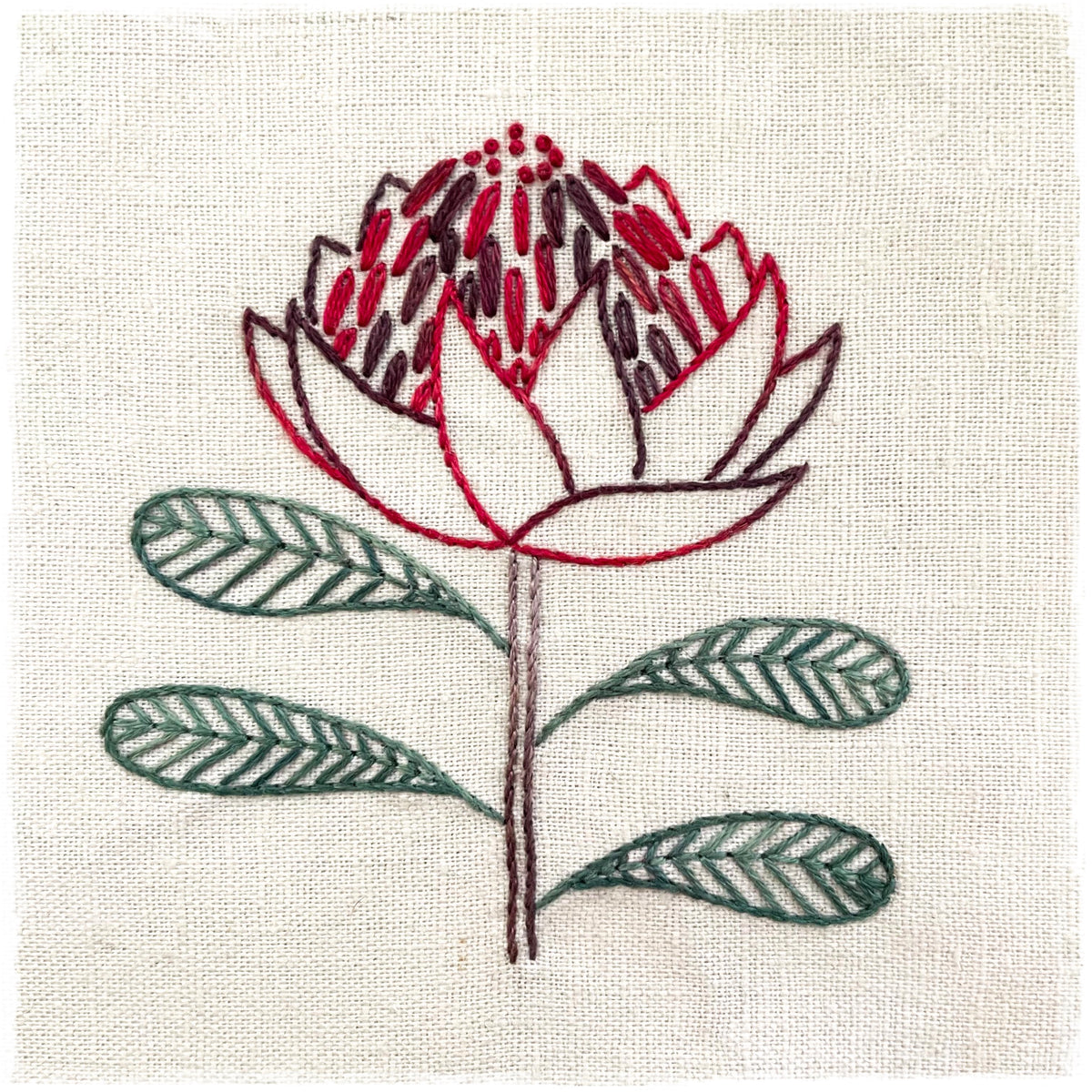 needlecraft pattern for a field journal, featuring a stitched design of a lily flower on a linen background with color instructions.