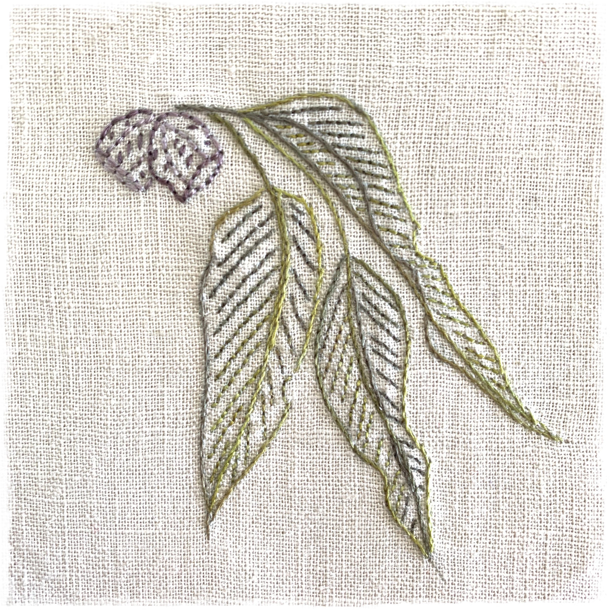 needlecraft canvas with a stitched leaf design in various colors on a beige background