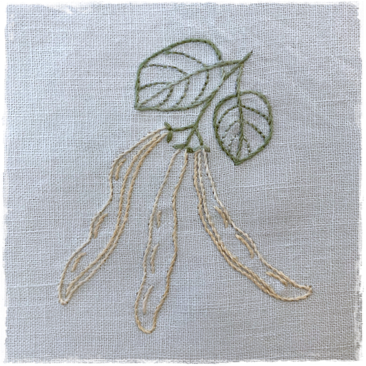 single journal page with a needlecraft design featuring a green leaf and beige pod-like stitching on a white background