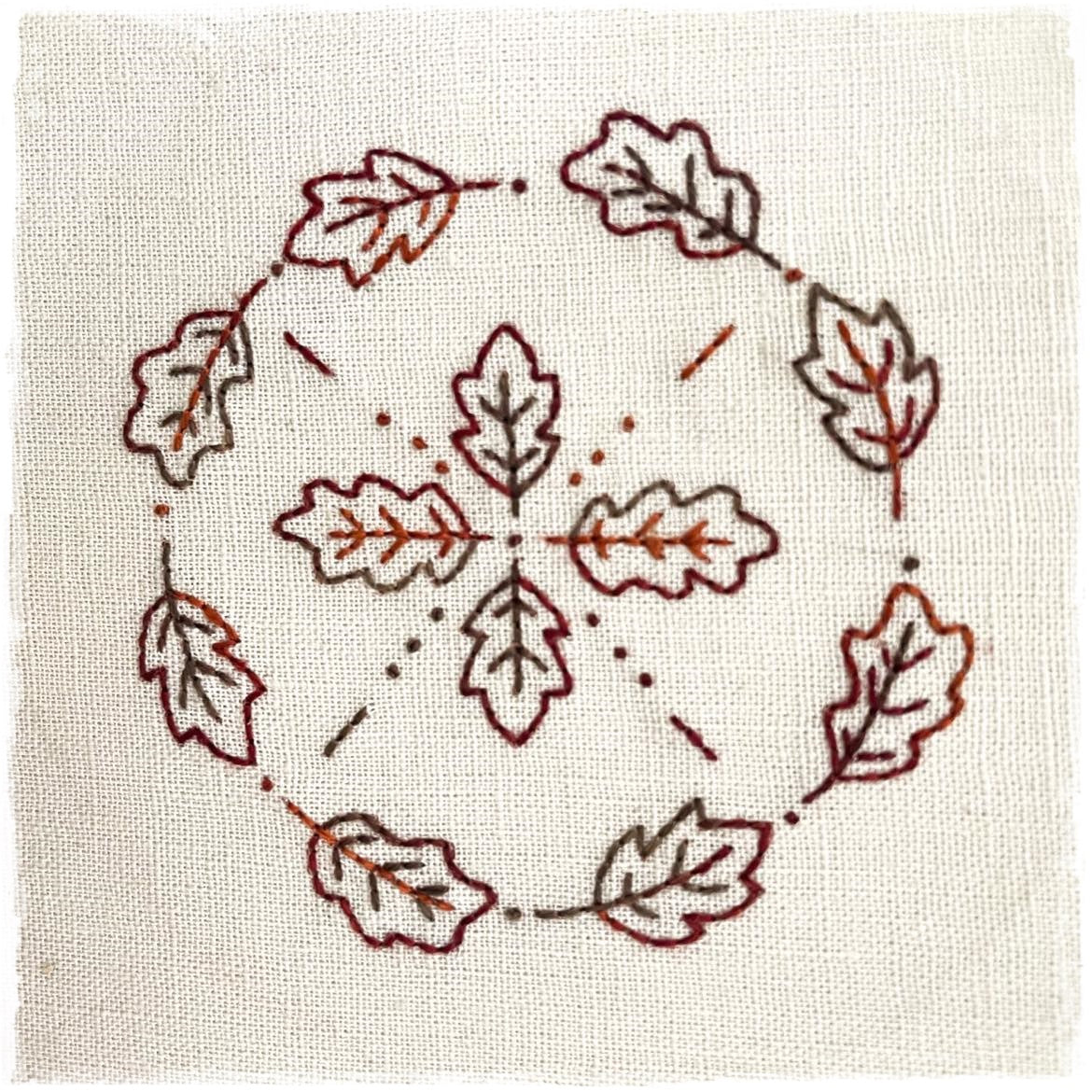 quilted journal page featuring a circular design with stylized leaves in various shades of green and brown, and a central knot of thread