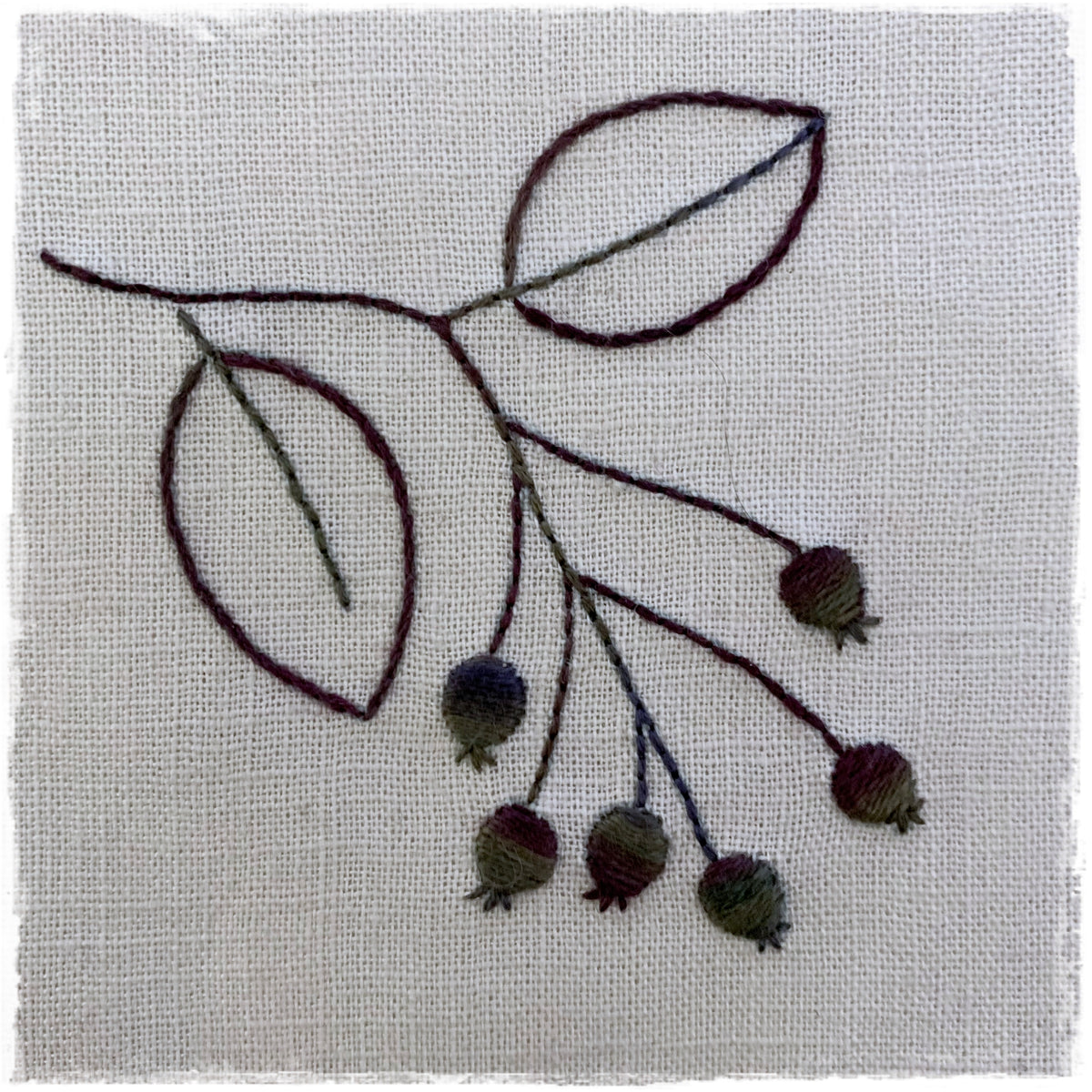 needlecraft pattern featuring a stitched leaf design on a linen background.