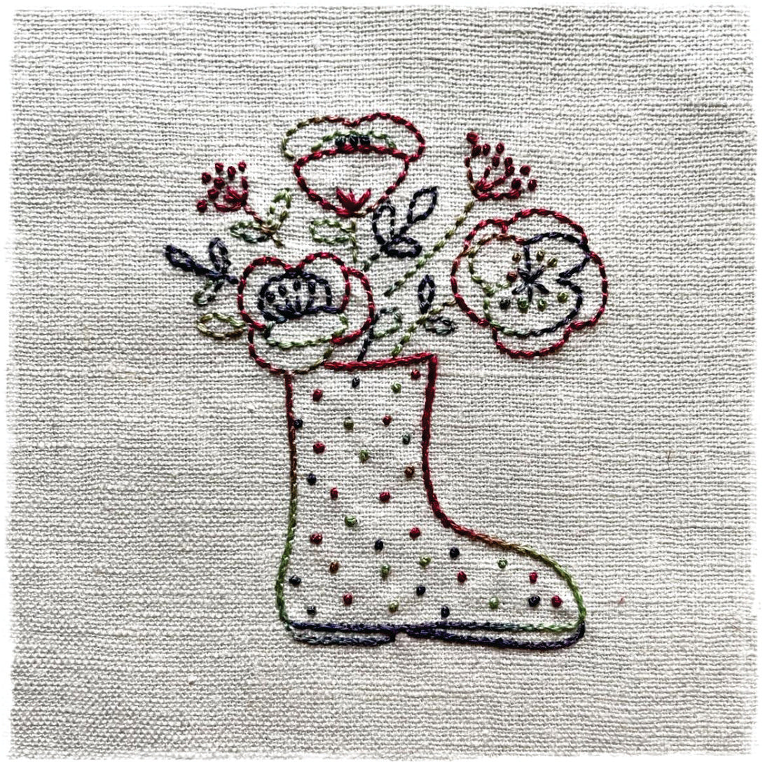 needlecraft pattern for a quilt, featuring a design resembling a boot with flowers, stitched on a linen background.