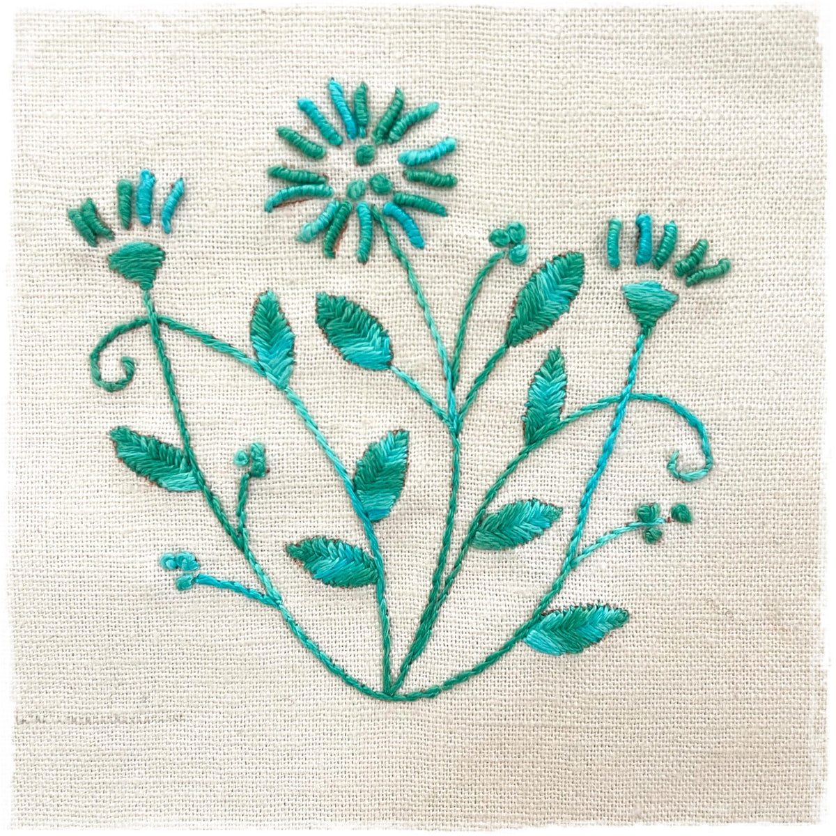 stitched linen journal page with a floral design, predominantly in green and blue colors.