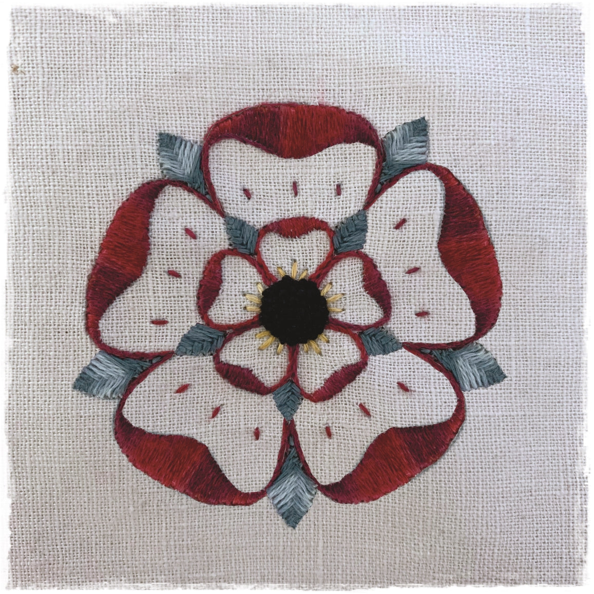 stitched journal page featuring a floral design with red, white, and gray colors on a linen background.