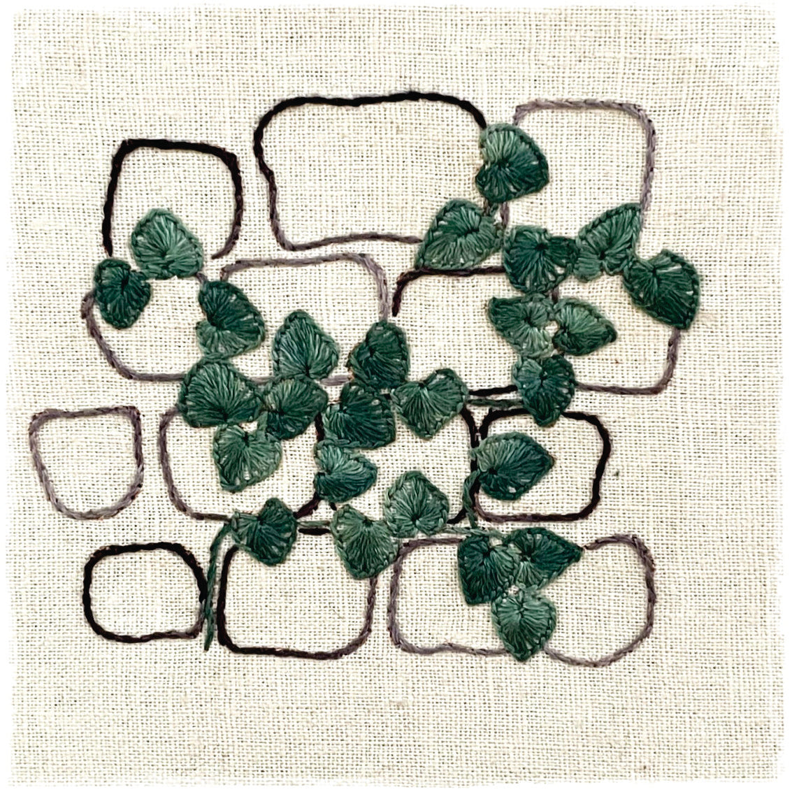 needlecraft canvas with a green floral design and the outlines of a trace-off pattern.