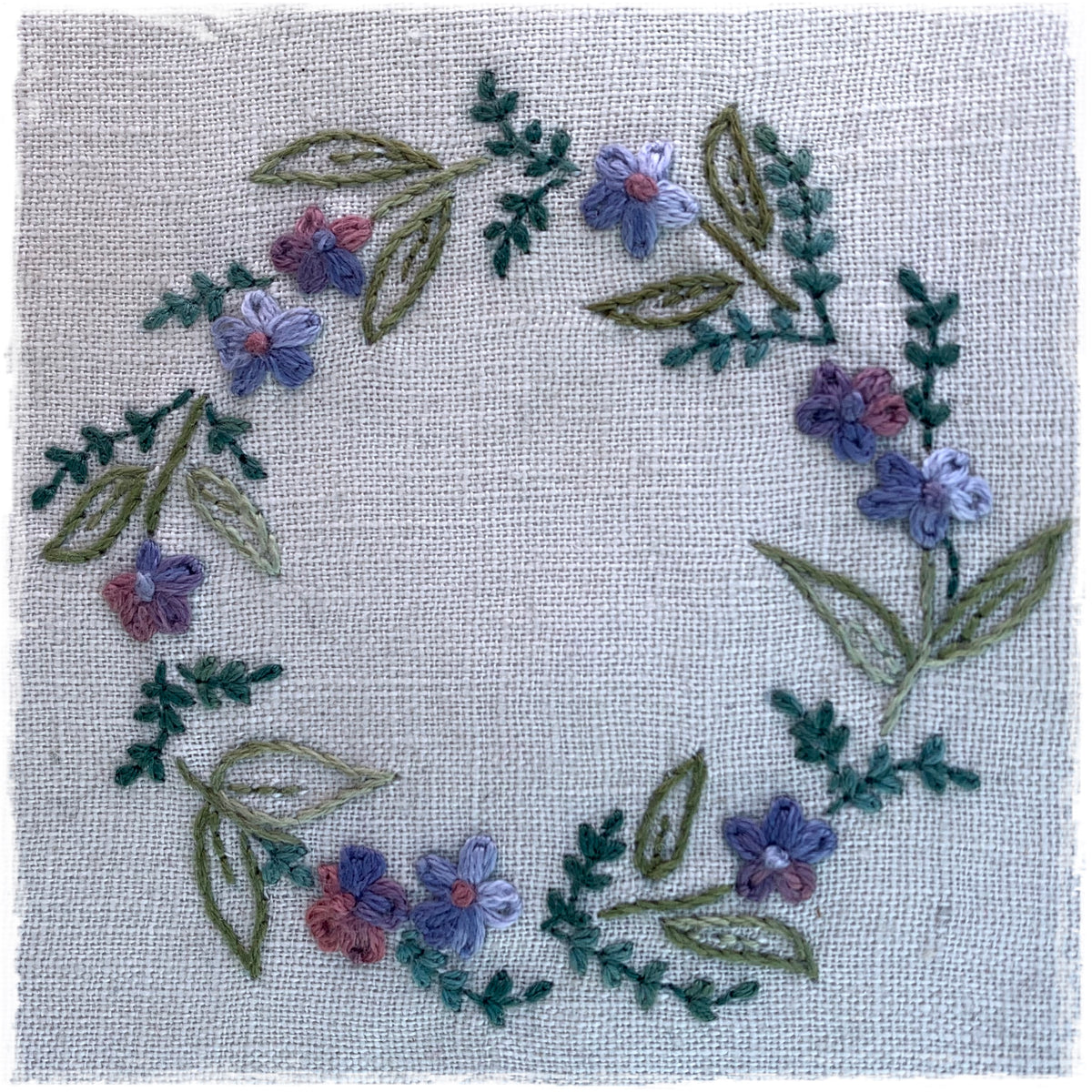 hand-stitched journal page featuring a floral design with various colors on a linen background.