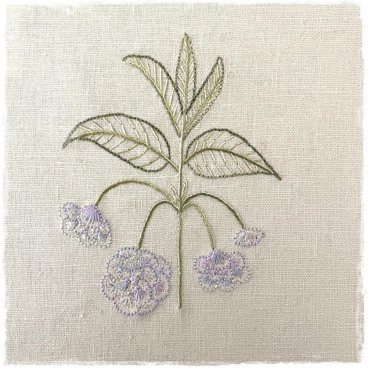 journal page with a needlecraft pattern for a quilt, featuring a stylized floral design with green and purple flowers on a linen background.