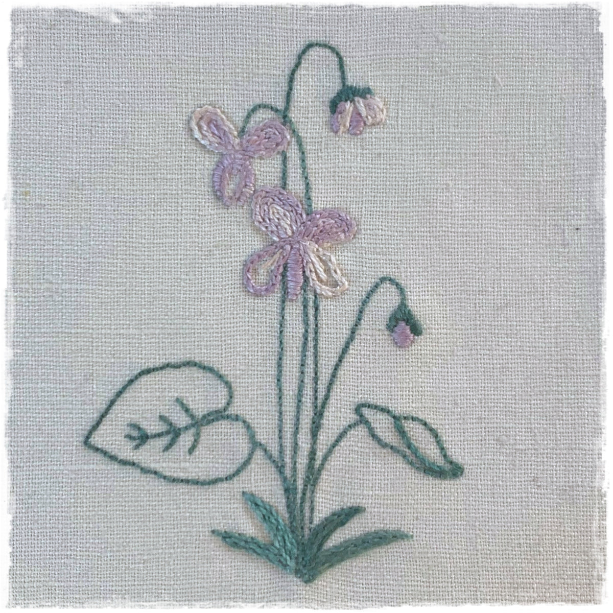 needlecraft pattern featuring a stitched floral design on linen fabric.