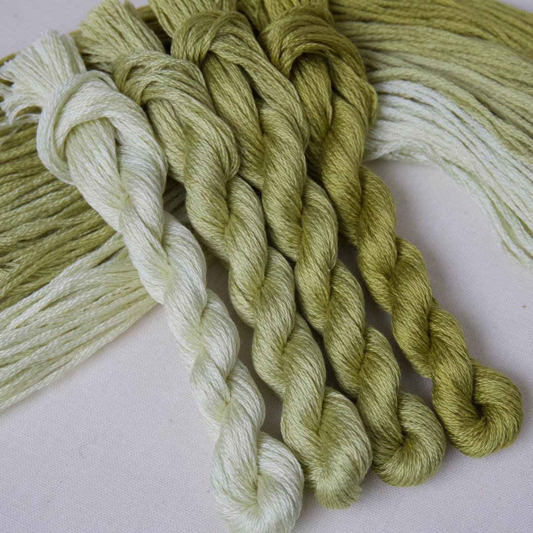 Four twisted skeins of embroidery thread in shades of palest green to olive.