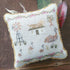 Embroidered pillow with a mother Emu and chicks, an Australian farmhouse and windmill design on a wooden surface.