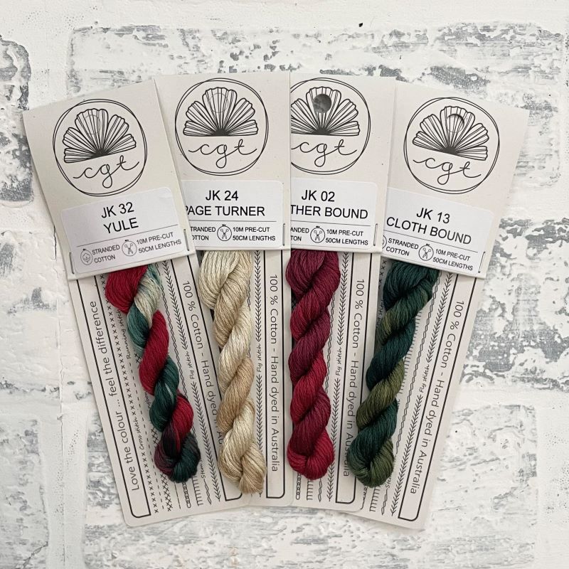 Four skeins of Crafting Club brand embroidery threads in red, green, and white colors, labeled as Yule, Leather bound, Page Turner, and Cloth Bound