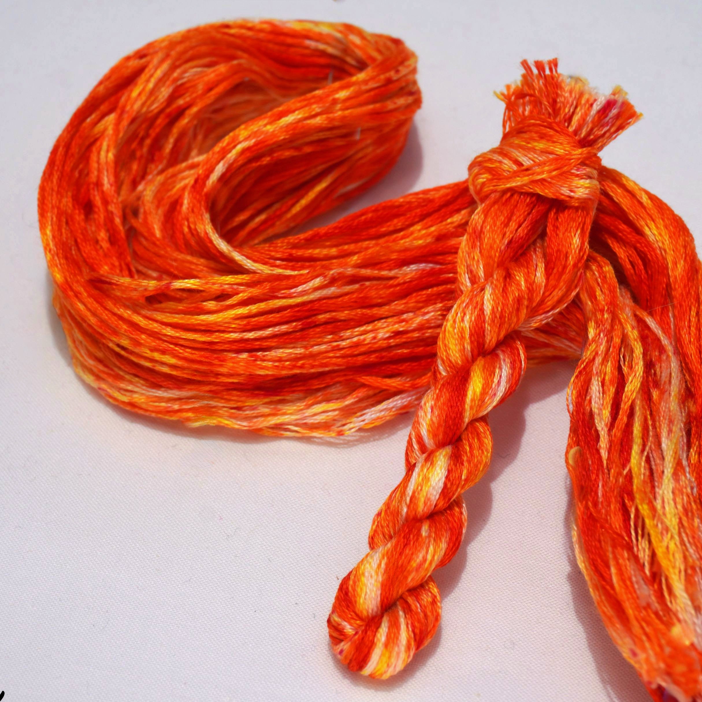 Embroidery thread with orange and yellow speckles on a white background