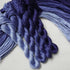 Four braided skeins of yarn in a blue-purple ombre gradient, arranged on a light off-white background.