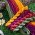 A close-up of four twisted skeins of colourful embroidery thread in olive green, mustard yellow, magenta, and coral pink.