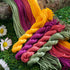 Arrangement of four thread skeins. The thread colours are olive green, magenta, coral pink, and yellow.