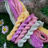 Four twisted skeins of embroidery thread in pastel shades of pink, yellow, purple, and sage green.