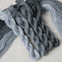 Several twisted skeins of yarn in soft blue-grey and charcoal tones.