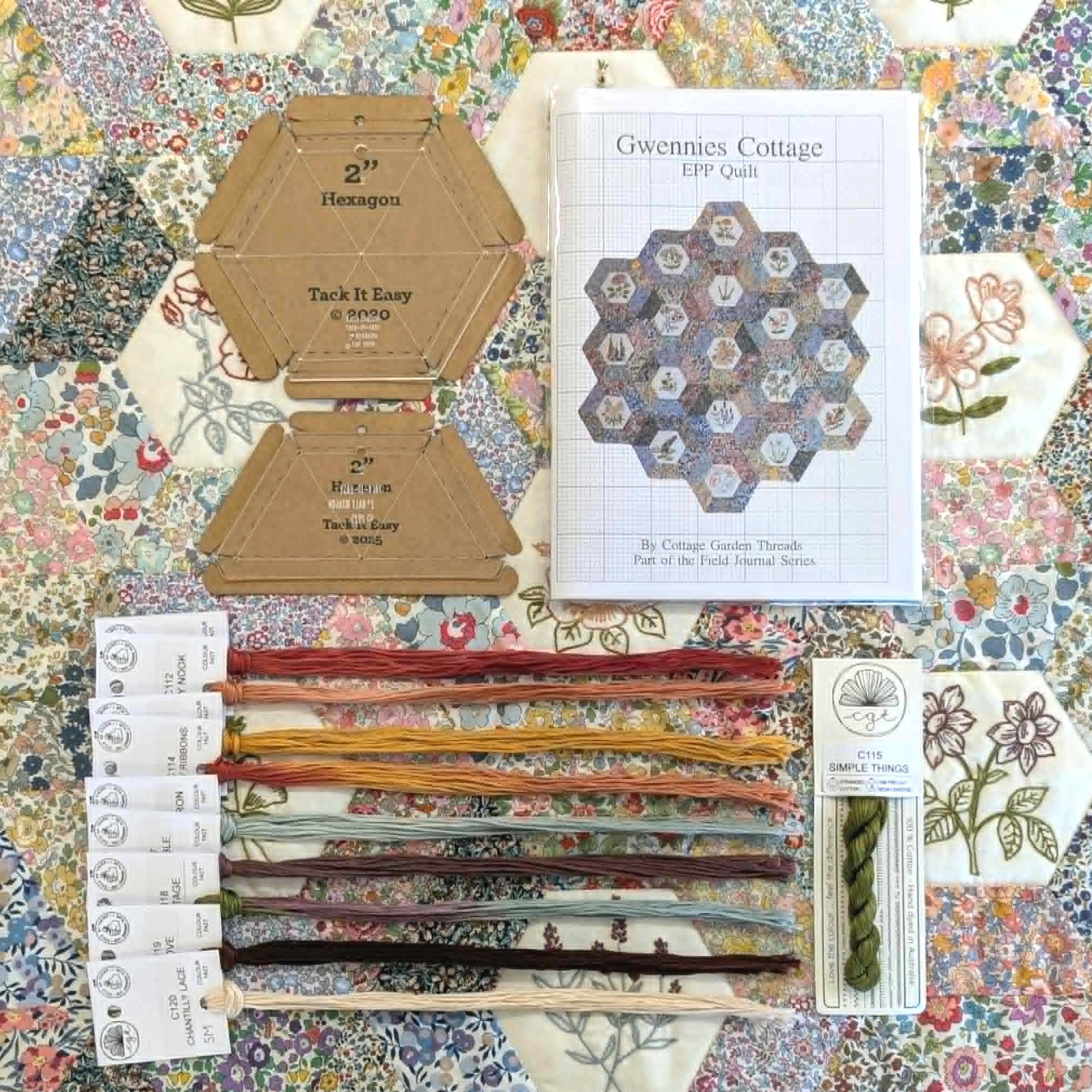 Quilting supplies including embroidery threads, pattern book, and templates on a floral background