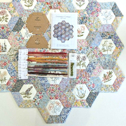 Hexagonal fabric samples with floral patterns and sewing tools and embroidery threads on a white background